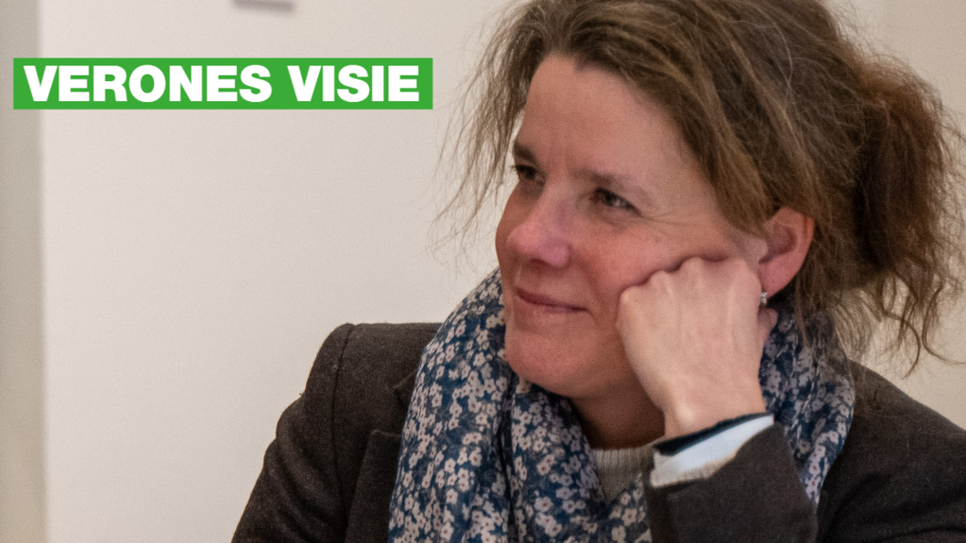 Verone Meengs - de Vries zit en leunt met haar hoofd op haar hand. Ze is een witte vrouw met bruin haar. Ze heeft een zwart jasje aan een een sjaal om.