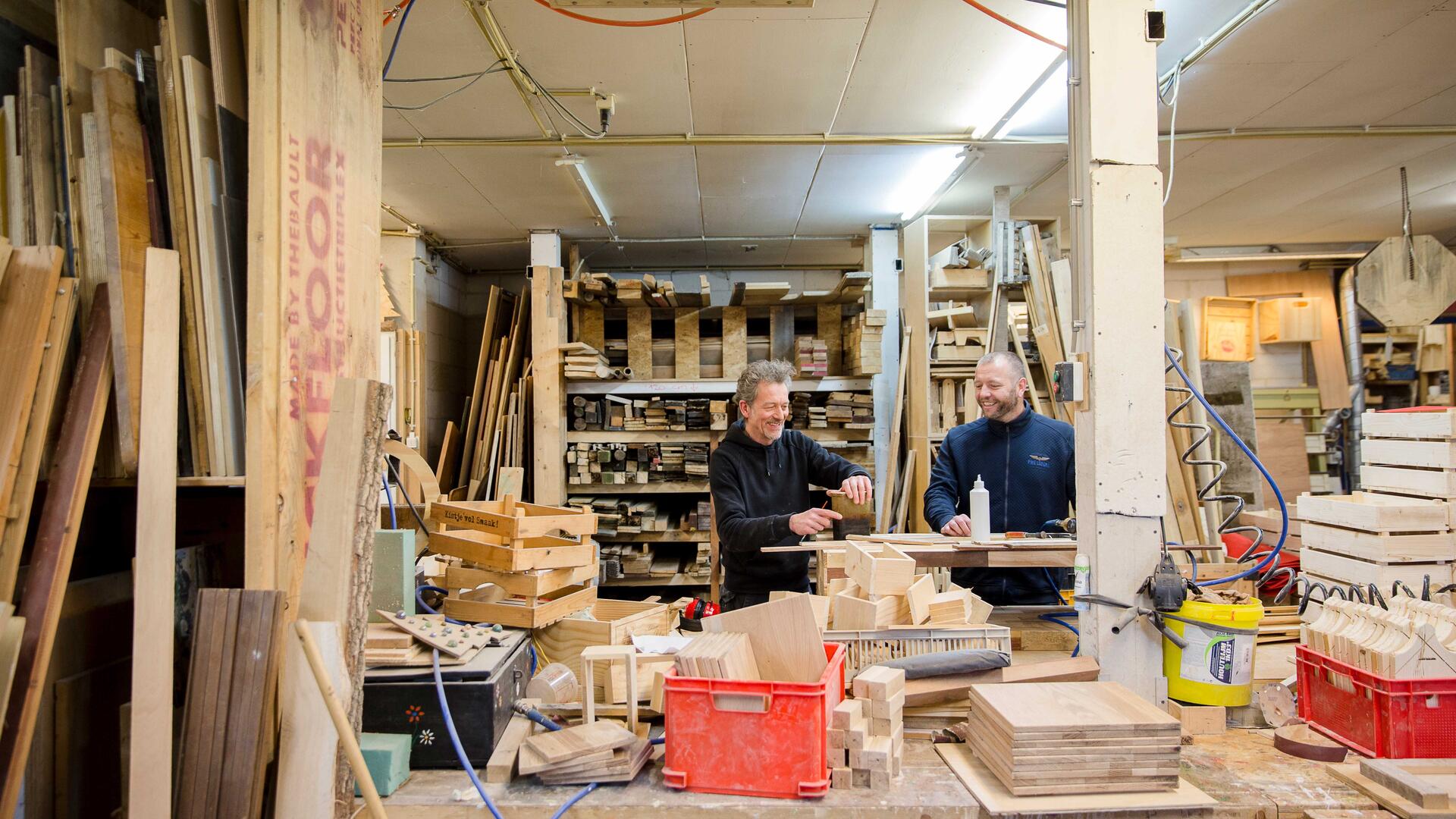 Twee mannen zijn aan het werk in een houtwerkplaats